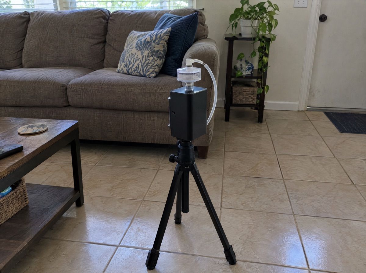 Small air sampling pump on a tripod in a living room.