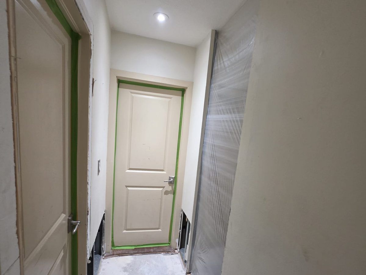 Hallway with a door taped off and plastic sheeting covering a wall opening.