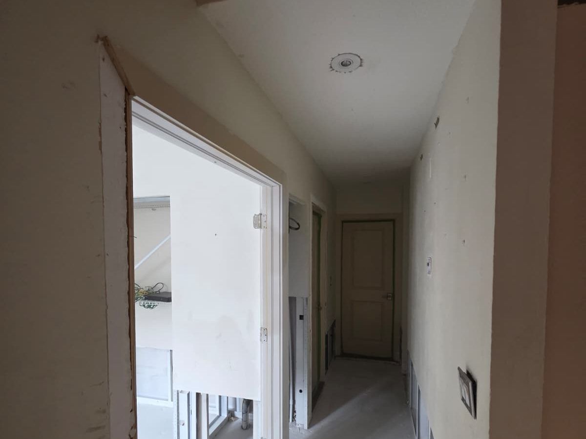 Empty hallway and doorway with the lower drywall removed along the walls.