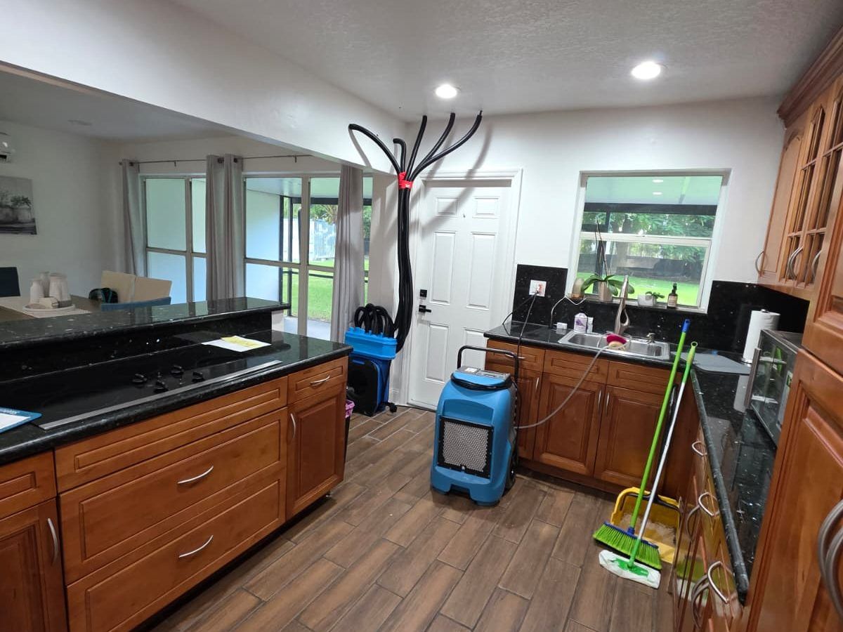 Dehumidifier and drying hoses set up in a kitchen.