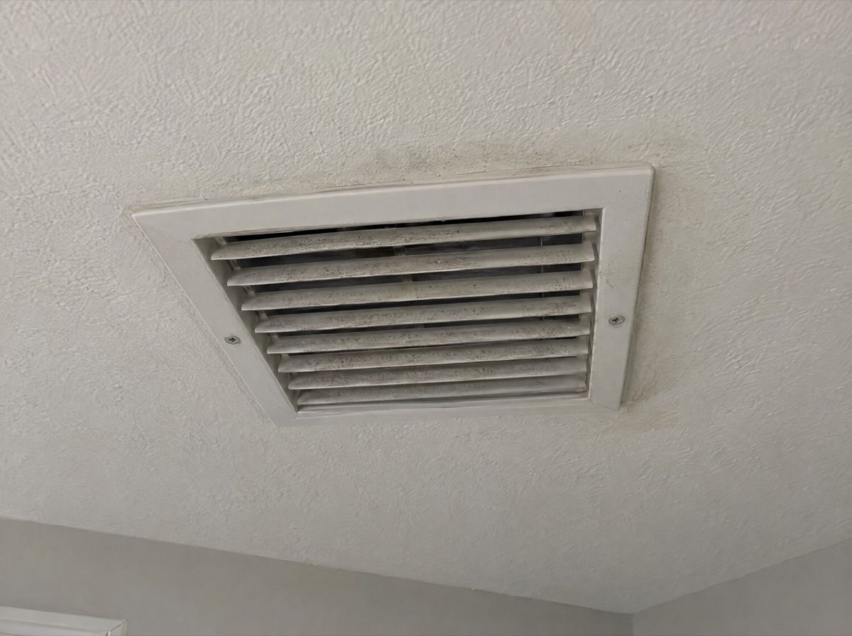 Ceiling air vent with light gray dust spots on the louvers.
